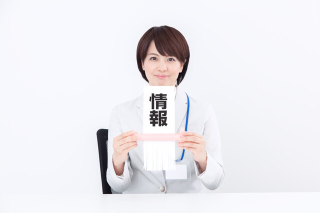 「情報」と書かれた紙を持つ女性